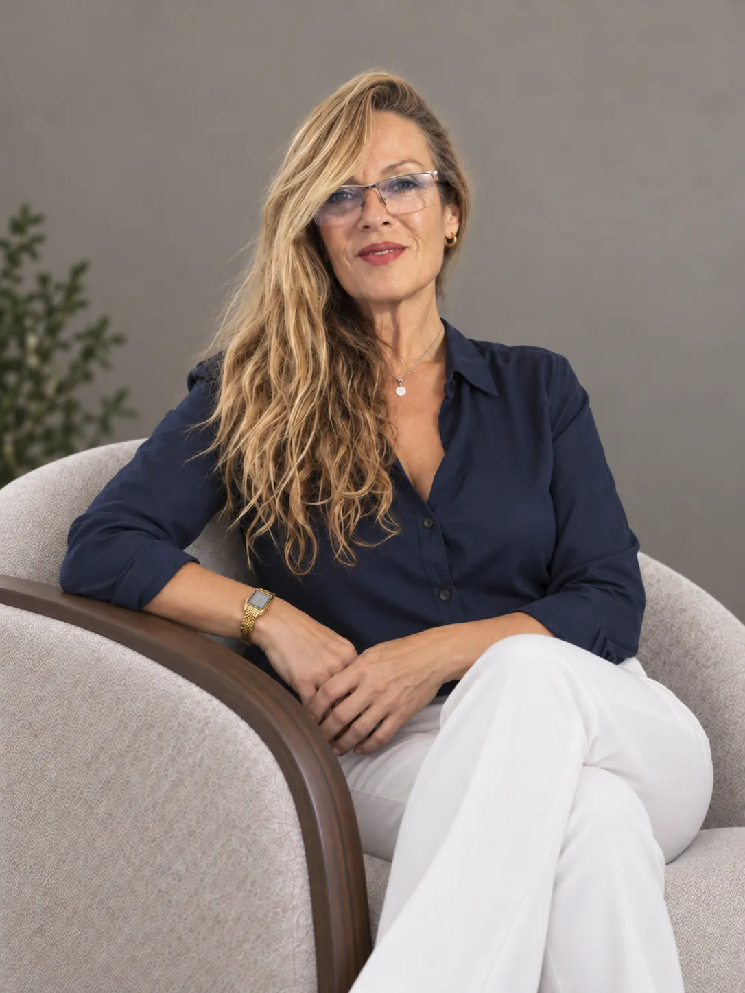 Olga Casteres sentada en un sillón con blusa azul marino, terapeuta especializada en dependencia emocional en Granada
